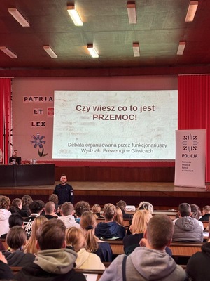młodzież siedząca w ławkach na auli w Komendzie Miejskiej Policji w  Gliwicach, widok na prezentację