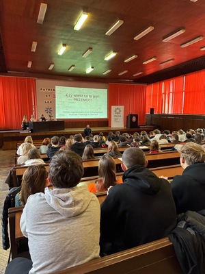 młodzież siedząca w ławkach na auli w Komendzie Miejskiej Policji w  Gliwicach - widok od drugiej strony od tyłu.