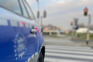 Na zdjęciu bok radiowozu policyjnego stojącego na tle przejścia dla pieszych.