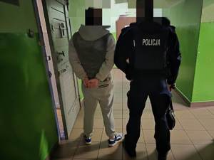 Na zdjęciu widzimy zatrzymanego wraz z umundurowanym policjantem stojących na korytarzu.