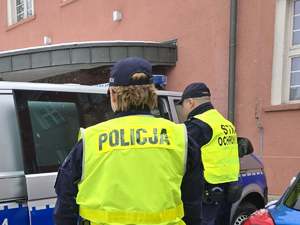 Funkcjonariusz Służby Ochrony Kolei i Policji przy radiowozie