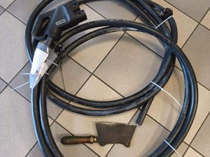 Odcięte kable ładowania od dystrybutora ładowania prądu oraz przedmiot przypominający tasak