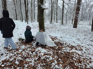 W lesie pod drzewem siedzi rozebrany mężczyzna, któremu pomocy udzielają harcerze. Obok stoją policjanci.