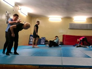 Na zdjęciu zajęcia z samoobrony dla kobiet w gliwickiej komendzie. Na macie prowadzone są ćwiczenia pod nadzorem instruktora.