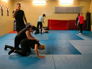 Na zdjęciu zajęcia z samoobrony dla kobiet w gliwickiej komendzie. Na macie prowadzone są ćwiczenia pod nadzorem instruktora.