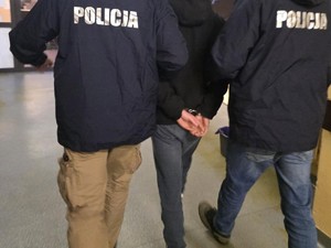 Dwóch policjantów prowadzi zatrzymanego