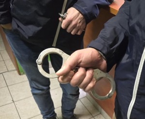 Policjant nieumundurowany trzyma w ręku kajdanki