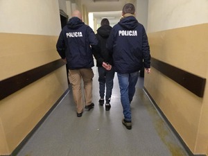 Policjanci prowadzą zatrzymanego korytarzem