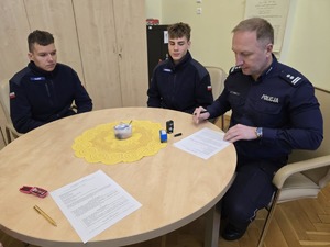 Komendant Miejski Policji w Gliwicach wraz z uczniami klasy policyjnej siedzą przy stole.
