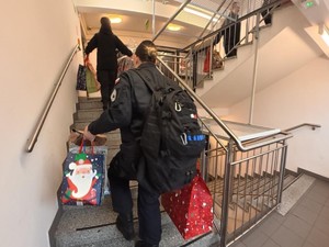 Policjanci i uczniowie klas mundurowych wnoszą paczki po schodach do Ośrodka Pomocy Społecznej