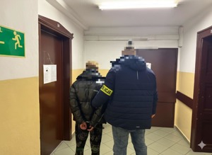 Na zdjęciu nieumundurowany policjant prowadzi zatrzymanego.
