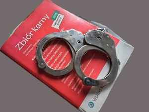 Książka z przepisami karnymi, na której leżą kajdanki