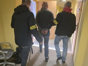 Dwóch policjantów prowadzi zatrzymanego
