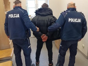 zatrzymanego mężczyznę trzyma pod ręce dwóch policjantów.