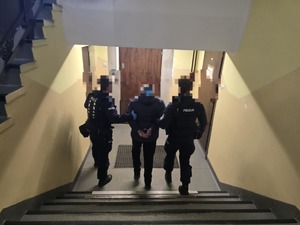Policjanci stoją z zatrzymanym przy drzwiach