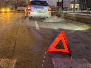 Pojazd stojący na jezdni w pobliżu przejścia i trójkąt ostrzegawczy na drodze