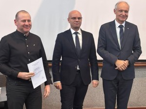 Na zdjęciu trzech mężczyzn: uczestnik kursu oraz dwóch organizatorów pozują do fotografii.