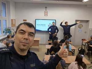 Na zdjęciu dzielnicowy na tle klasy uczestniczącej w pogadance