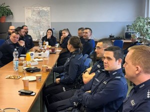 Na zdjęciu po obu stronach długiego stołu siedzą umundurowani policjanci
