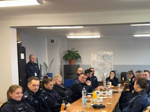 Przedstawiciele Ośrodka Pomocy Społecznej w Gliwicach i dzielnicowi rozmawiają siedząc przy długim stole