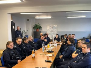 Przedstawiciele Ośrodka Pomocy Społecznej w Gliwicach i dzielnicowi rozmawiają siedząc przy długim stole