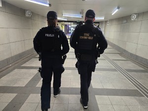 Policjant i funkcjonariusz Straży Ochrony Kolei na patrolu na dworcu.