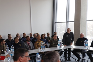 Zaproszeni goście podczas narady siedzą na dużej sali.