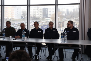 Policjanci siedzą na sali przy stole.