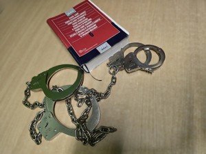 Na stole leżą kajdanki i kodeks karny