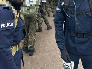 W oczekiwabu na start dwóch policjantów stoi w grupie umundurowanych żołnierzy
