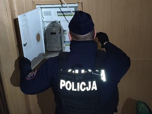 Na zdjęciu widać policjanta stojącego przy liczniku energii elektrycznej.