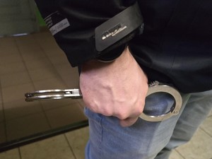 Policjanci prowadzą zatrzymanego w pomieszczeniu dla osób zatrzymanych