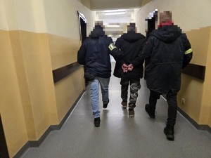 Dwóch policjantów prowadzi zatrzymanego korytarzem