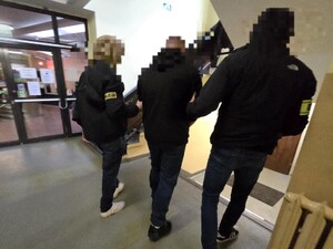 Zatrzymanego prowadzą korytarzem policjanci