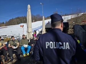 Policjanci prowadzą zajęcia dla uczniów klas mundurowych. W tle widać stok narciarski
