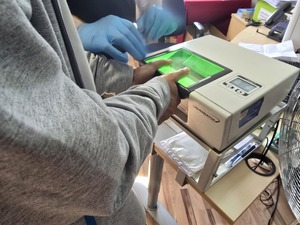 Pobieranie odcisków palców od zatrzymanego przez technika kryminalistyki