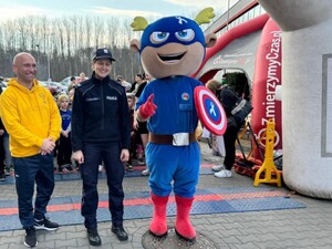 Na linii starty policjantka z mężczyzną-dyrektorem szkoły oraz maskotką.