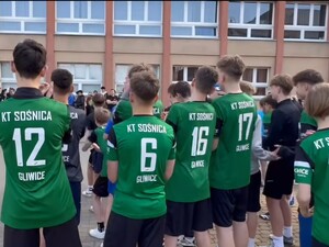 Uczestnicy biegu w zielonych koszulkach stoją przed startem