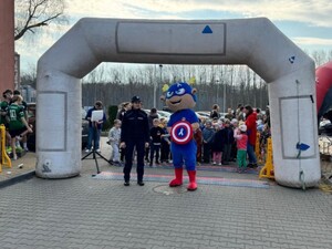 Na starcie biegu stoi policjantka wraz z maskotką