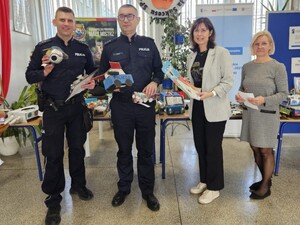 Dwóch policjantów mi dwie kobiety pozują do zdjęcia demonstrując prace plastyczne