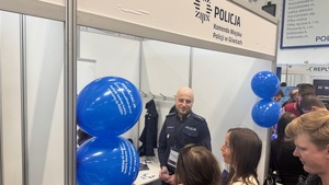 Na zdjęciu widać stanowisko policyjne oraz policjanta rozmawiającego z dwoma kobietami.