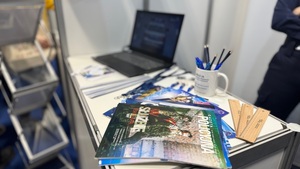 Na zdjęciu są widoczne gadżety rozłożone na stanowisku policyjnym - gazetki policyjne, długopisy, ołówki oraz linijki.