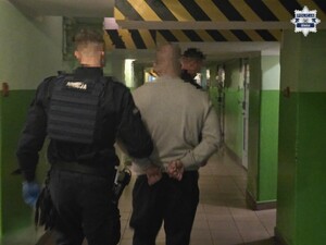 Policjant prowadzi korytarzem osobę zatrzymaną