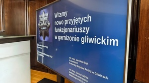 Na zdjęciu widzimy tablicę z logiem gliwickiej Komendy oraz zapisem witamy nowo przyjętych policjantów