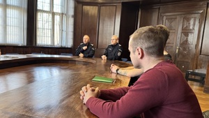 Na zdjęciu widzimy rozmawiących przy stole komendantów z nowo przyjętymi policjantami.