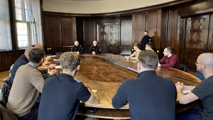 Na zdjęciu widzimy rozmawiących przy stole komendantów z nowo przyjętymi policjantami.