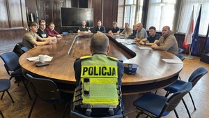Na zdjęciu widzimy rozmawiąjącego policjanta z ruchu drogowego  z nowo przyjętymi policjantami. Zdjęcie zrobione za plecami.