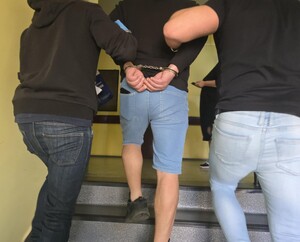 Policjanci prowadzą zatrzymanego po schodach