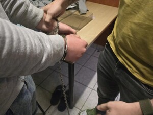 Policjant nieumundurowany zakłada kajdanki zespolone zatrzymanemu