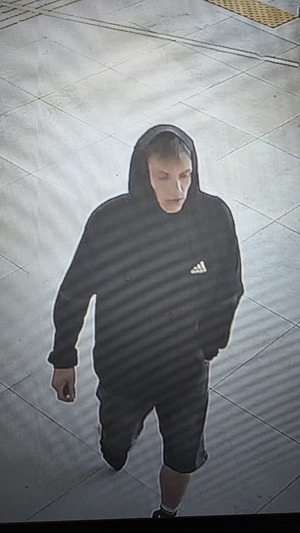 Na zdjęciu młody mężczyzna w ciemnej bluzie z kapturem na głowie, krótkich spodenkach i obuwiu sportowym